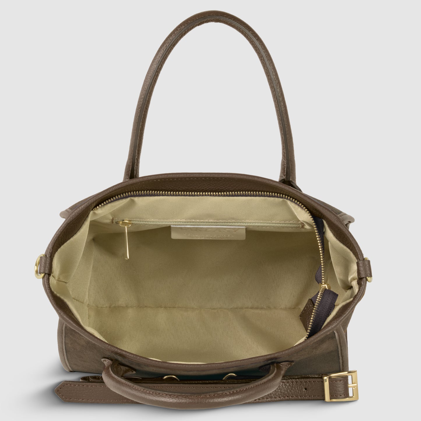 A brown suede leather handbag with gold hardware is shown open, revealing a spacious beige interior with a side pocket, zipper pull, and a small leather tag. Handcrafted in Florence, it features an adjustable detachable strap for versatile styling.