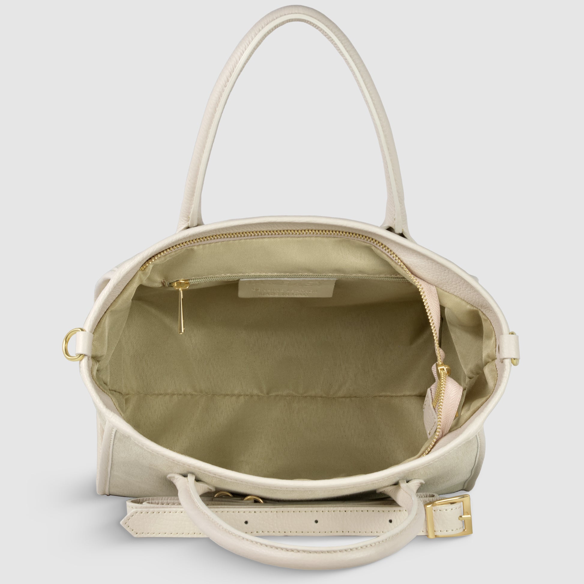 A top-down view of an open beige suede leather handbag with gold hardware, showing its spacious interior, a zippered side pocket, and an adjustable crossbody strap attached to the bag.
