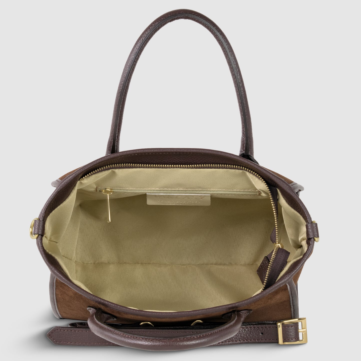 Top-down view of an open brown suede leather handbag with gold hardware, handcrafted in Florence, showing a spacious beige fabric interior, inner zipper pocket, and an adjustable detachable strap detail on the side.
