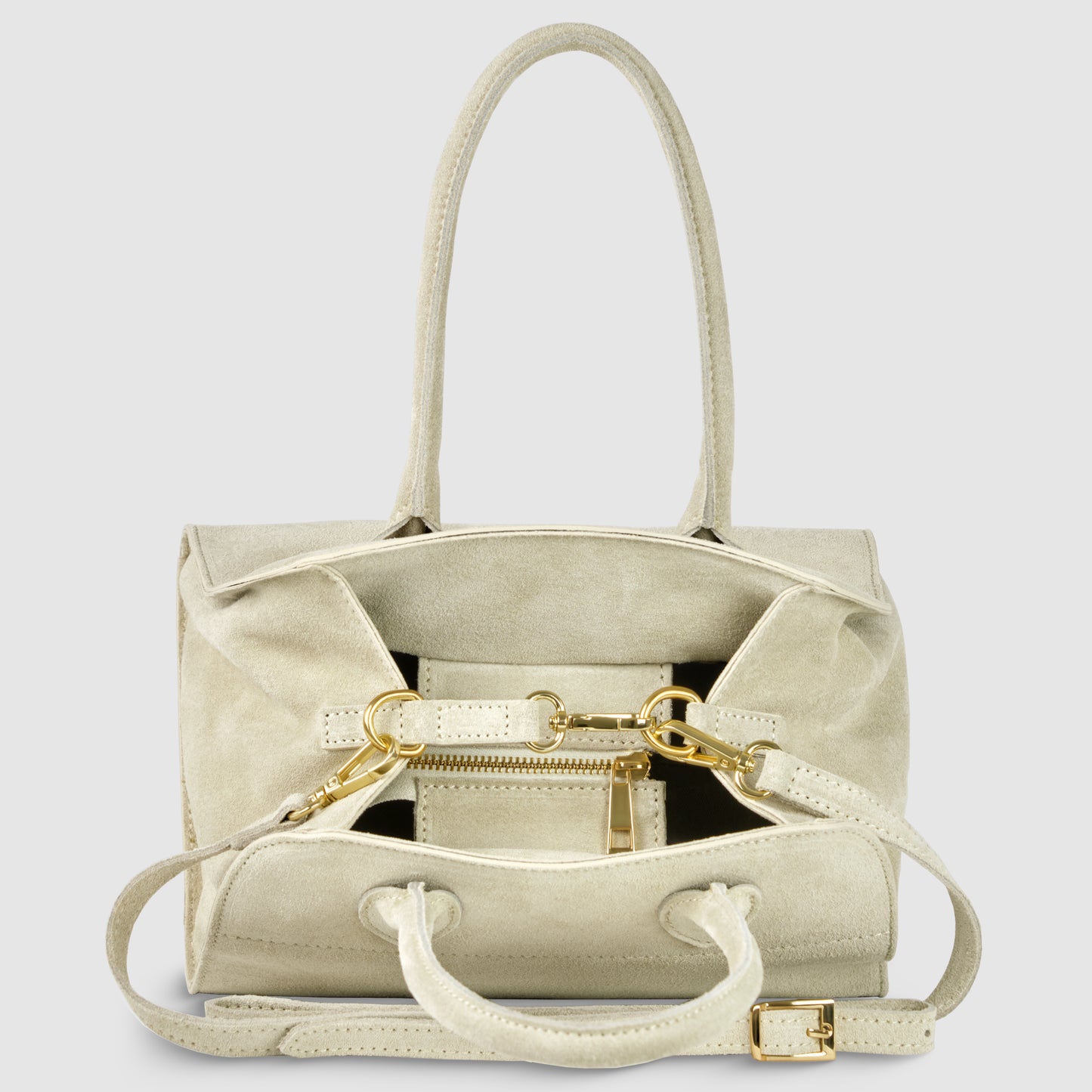 A handmade Italian handbag in beige genuine suede with gold hardware, two top handles, a detachable shoulder strap, and a front zipper pocket, sits against a plain light gray background.