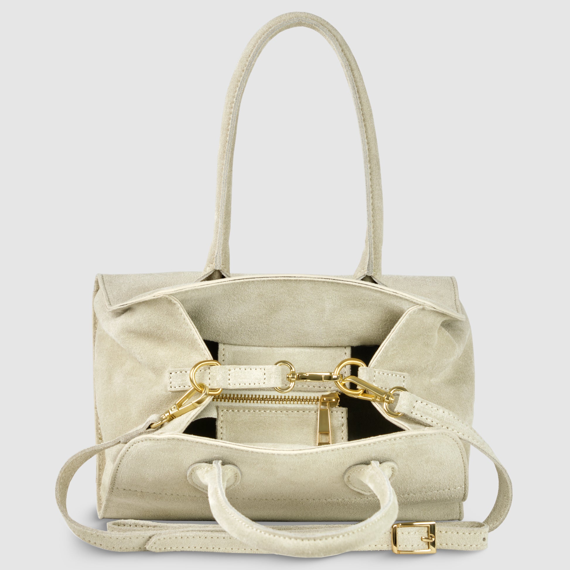 A handmade Italian handbag in beige genuine suede with gold hardware, two top handles, a detachable shoulder strap, and a front zipper pocket, sits against a plain light gray background.
