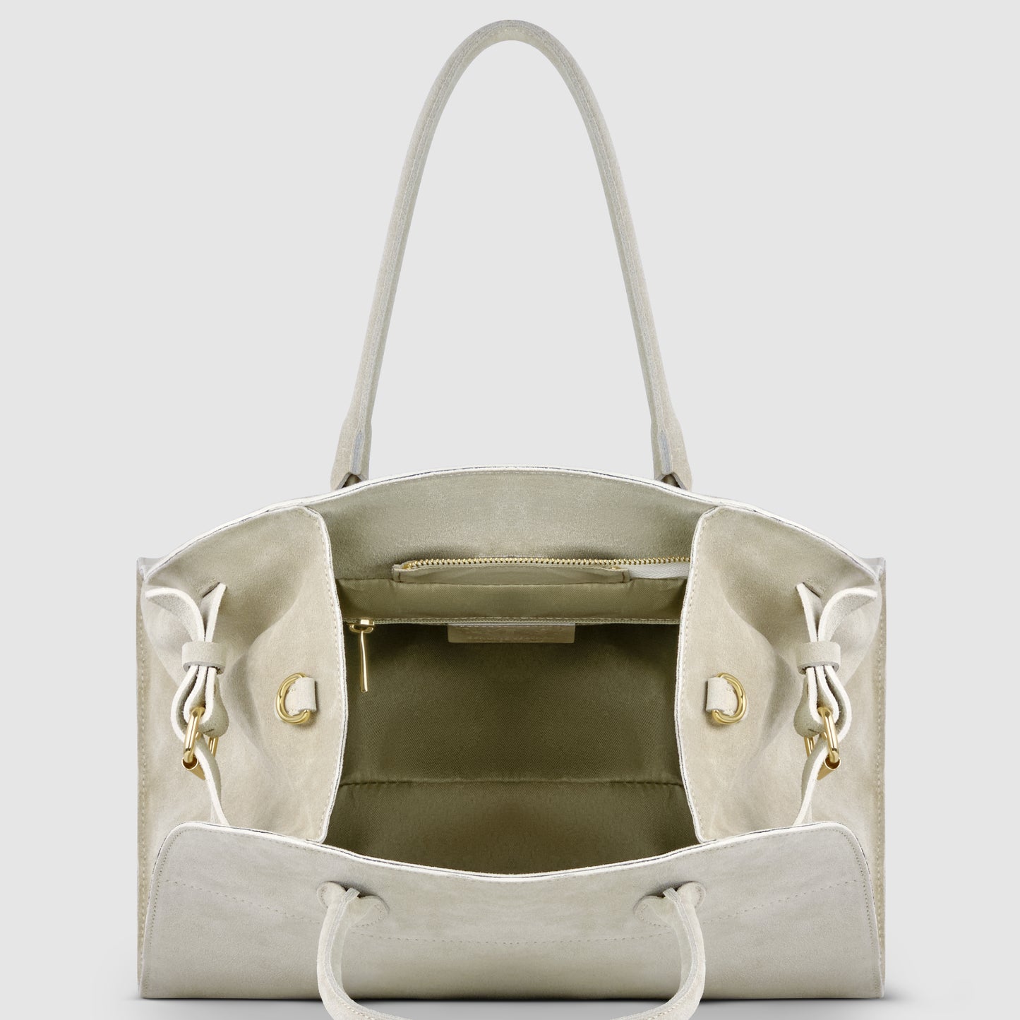 A beige Italian suede handbag with an open top, two handles, gold hardware, a zippered inner pocket, and two side pockets is displayed against a plain light background.