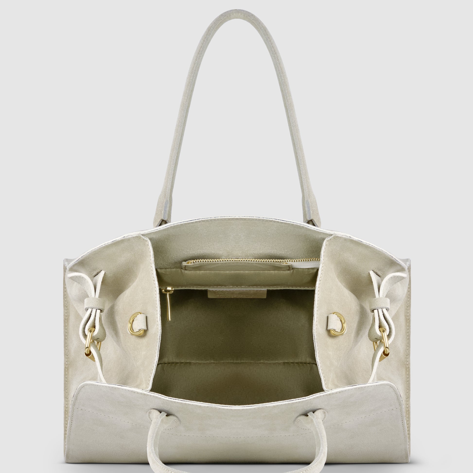 A beige Italian suede handbag with an open top, two handles, gold hardware, a zippered inner pocket, and two side pockets is displayed against a plain light background.