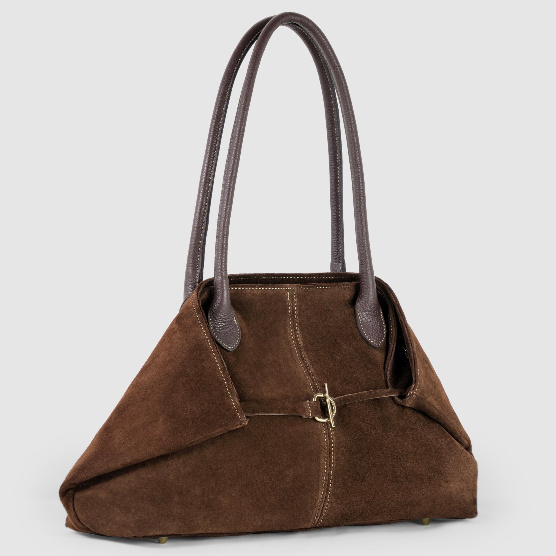 A women’s tote crafted from rich brown Italian suede, featuring long genuine leather handles and a small buckle detail on the front, displayed against a plain light gray background.