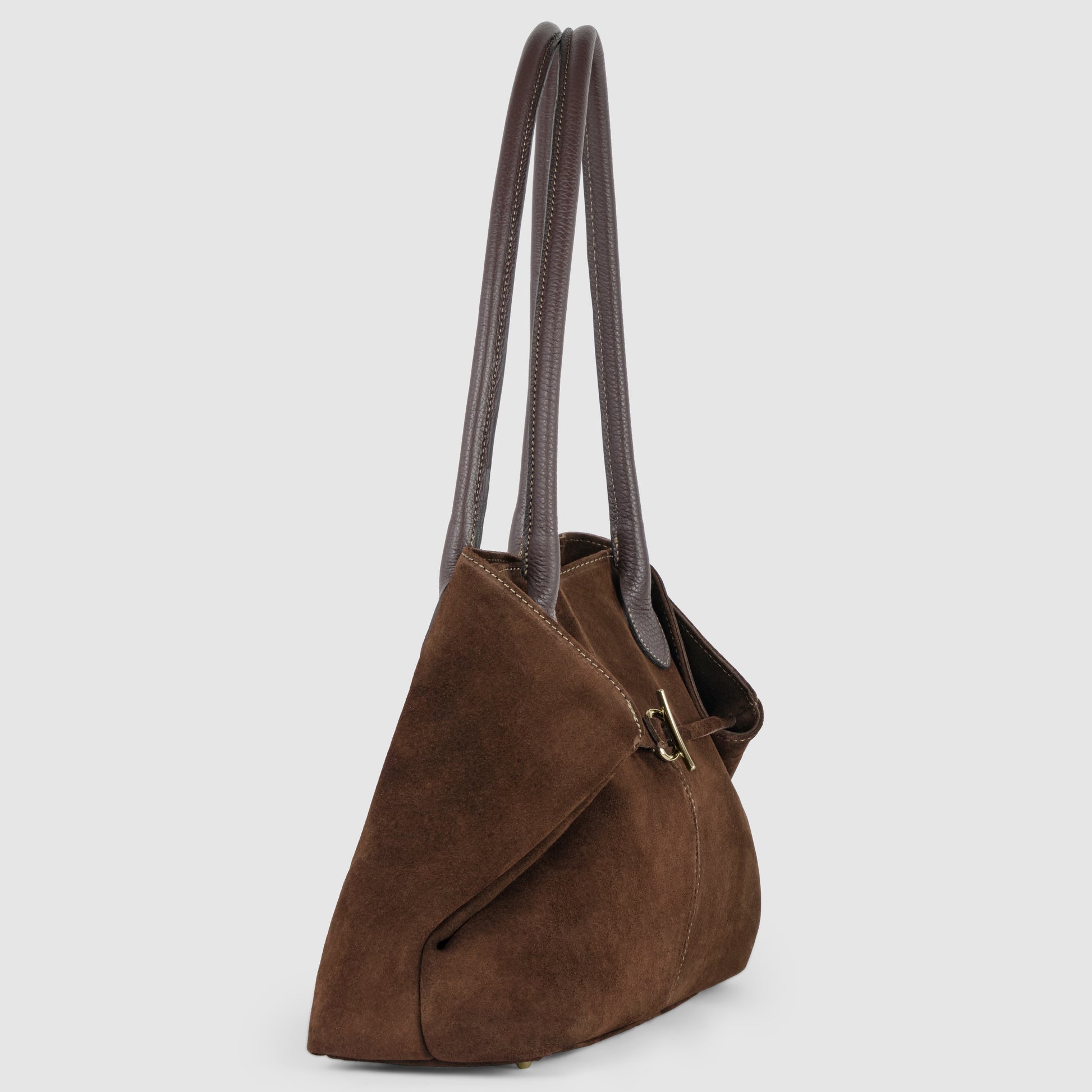 A women’s tote in brown Italian suede, featuring two long, dark brown genuine leather shoulder bag handles and a gold clasp, shown from a side angle against a plain light background.