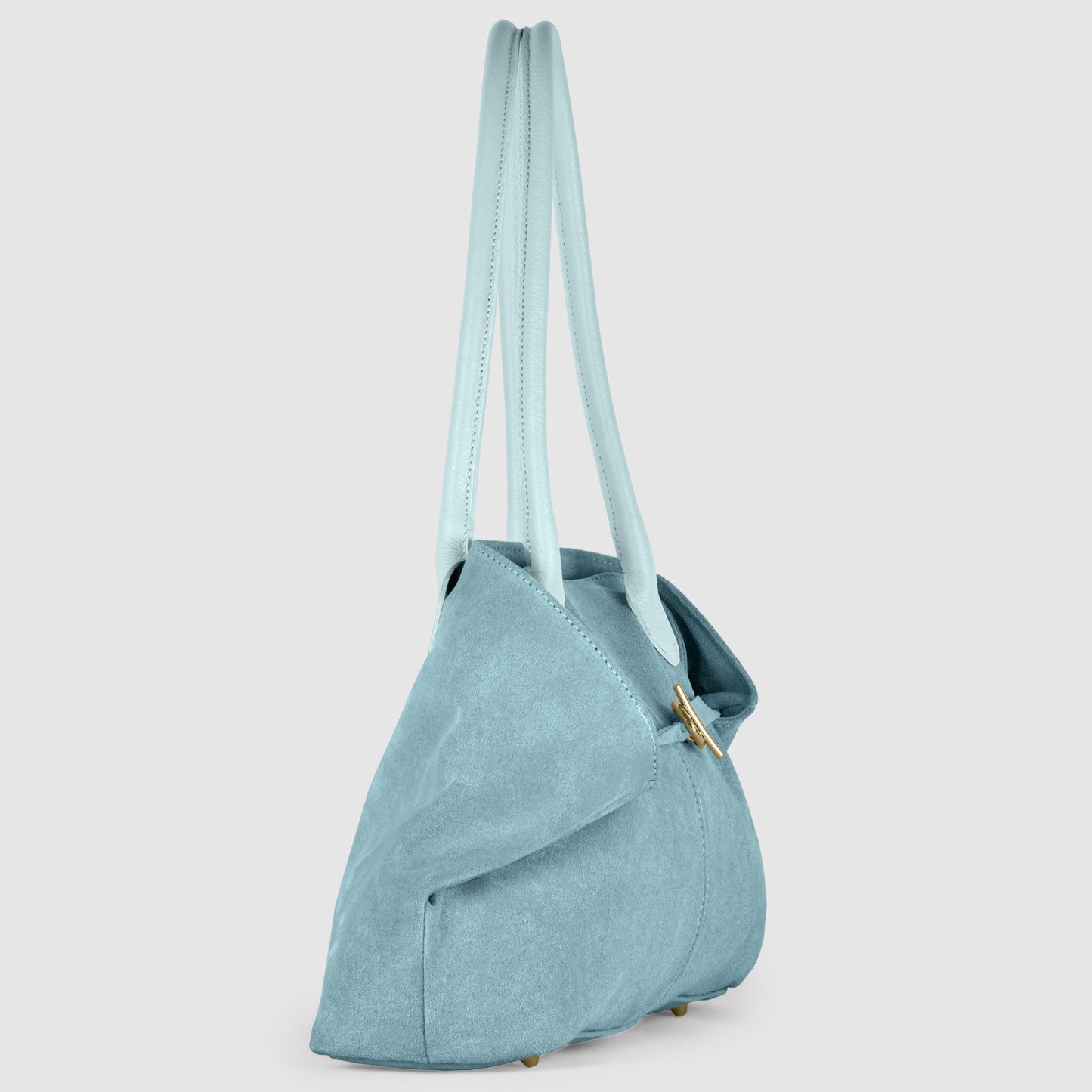 A light blue Italian-crafted suede tote bag with two long handles and a gold clasp, shown from the side on a plain white background. The bag has a soft, structured shape and is slightly open at the top.