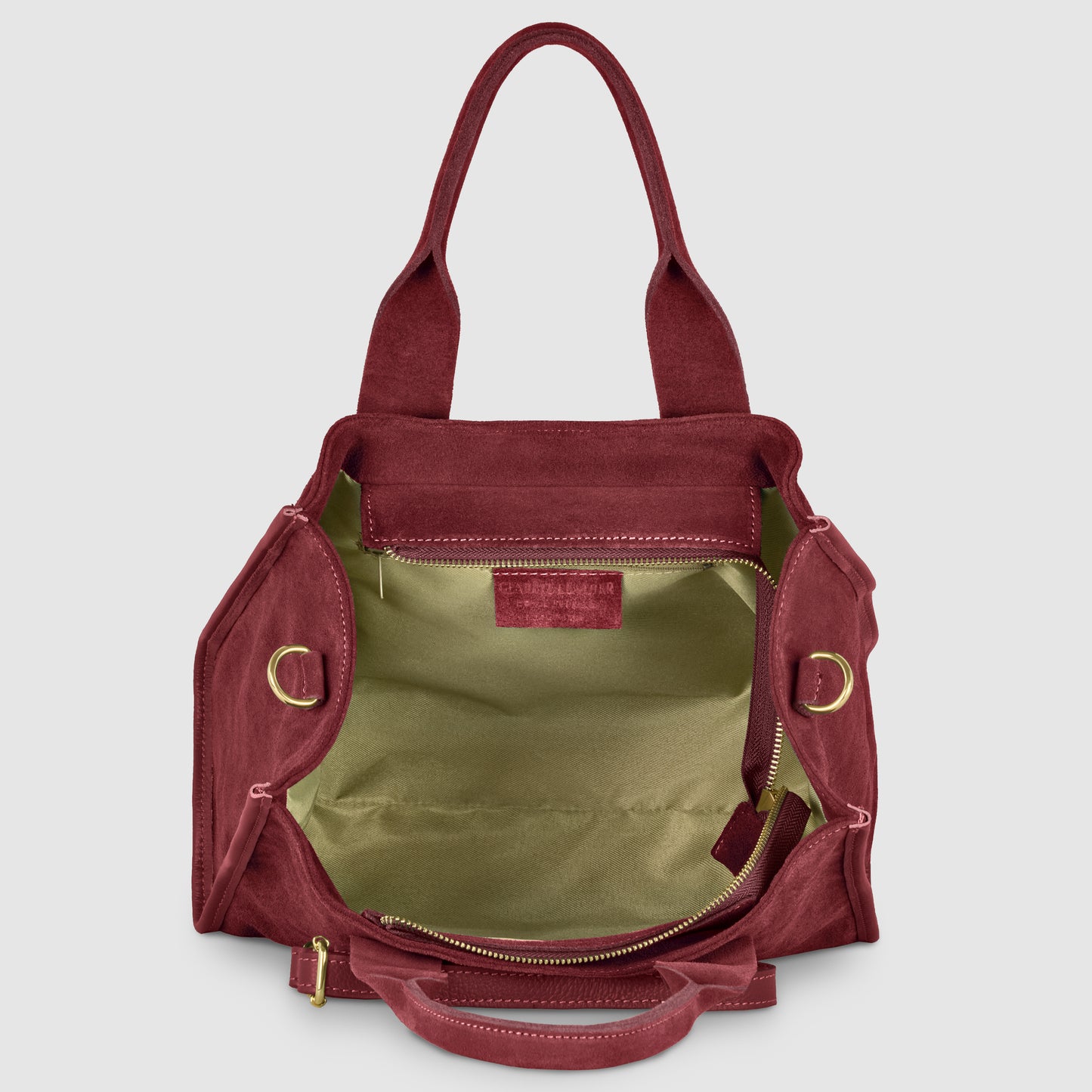 A burgundy suede bag with two handles, gold hardware, and a wide open top revealing a spacious light beige interior and an interior pocket—an elegant handmade Italian bag for any occasion.