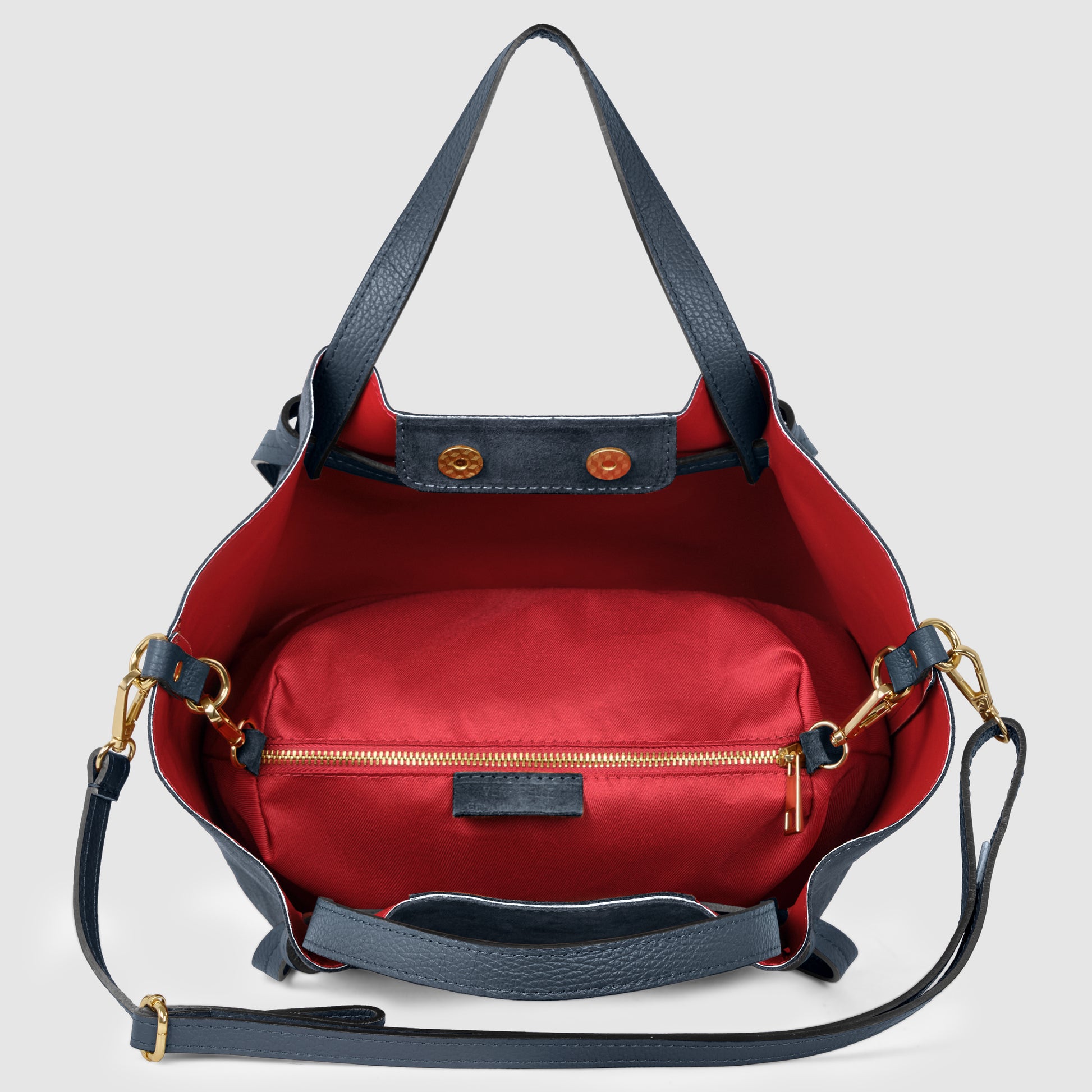 A navy blue handmade Italian bag with gold hardware, shown open to reveal a bright red interior and a zippered pouch inside. The bag has two handles and an adjustable shoulder strap, showcasing classic Florentine leatherwork.