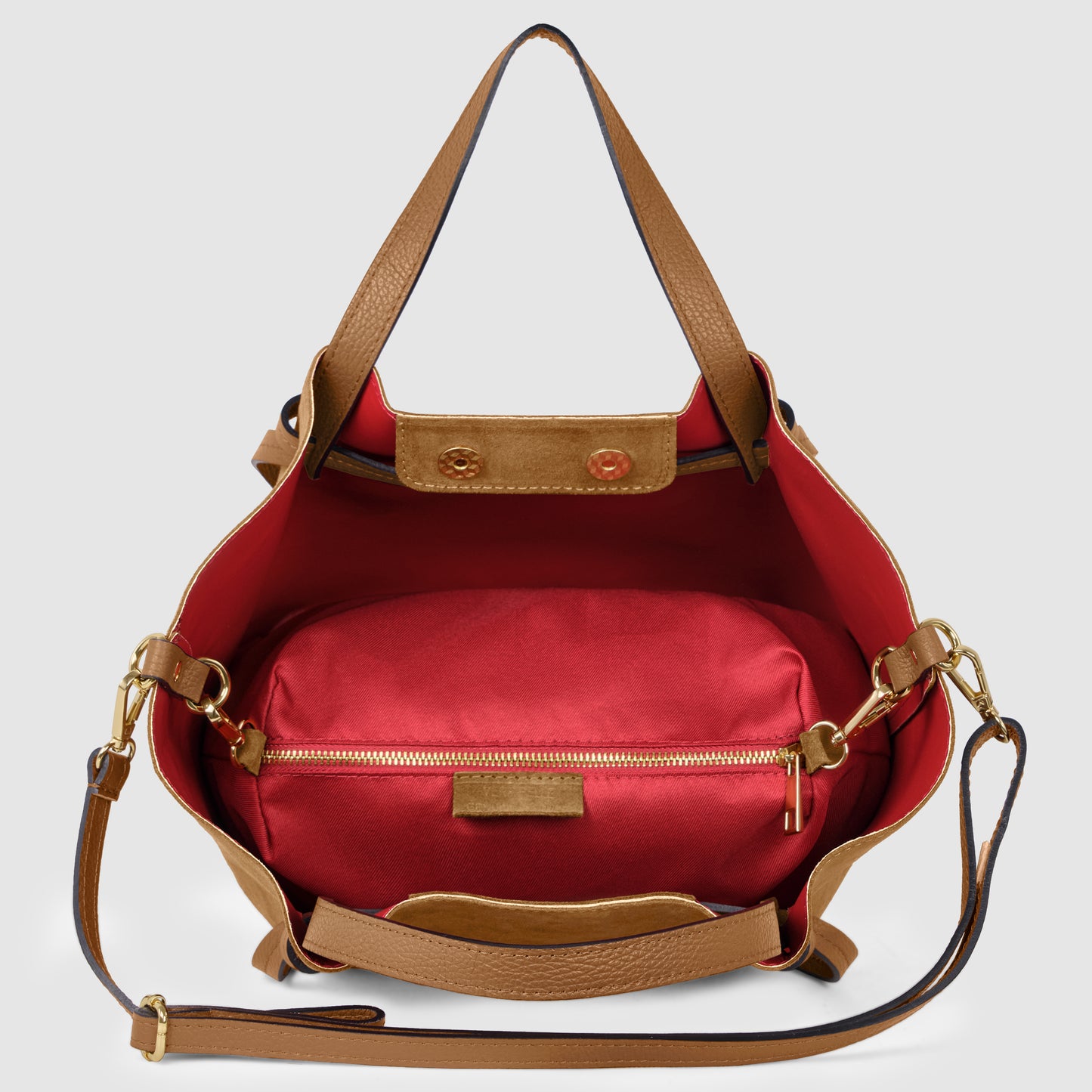 Open brown leather handmade Italian bag with a red fabric interior, gold zipper pocket, brown leather straps, and gold hardware, beautifully displayed against a light gray background.
