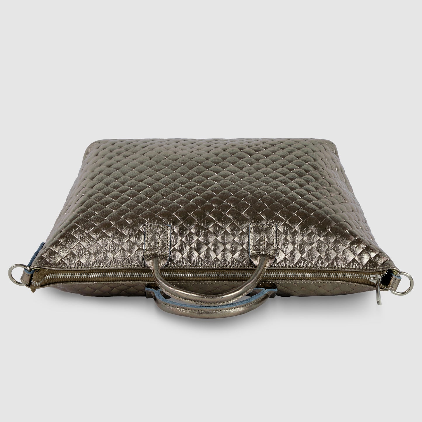 A metallic quilted leather handbag, inspired by Florentine leathercraft, features two handles, a zipper closure, and silver hardware, displayed against a plain light gray background.