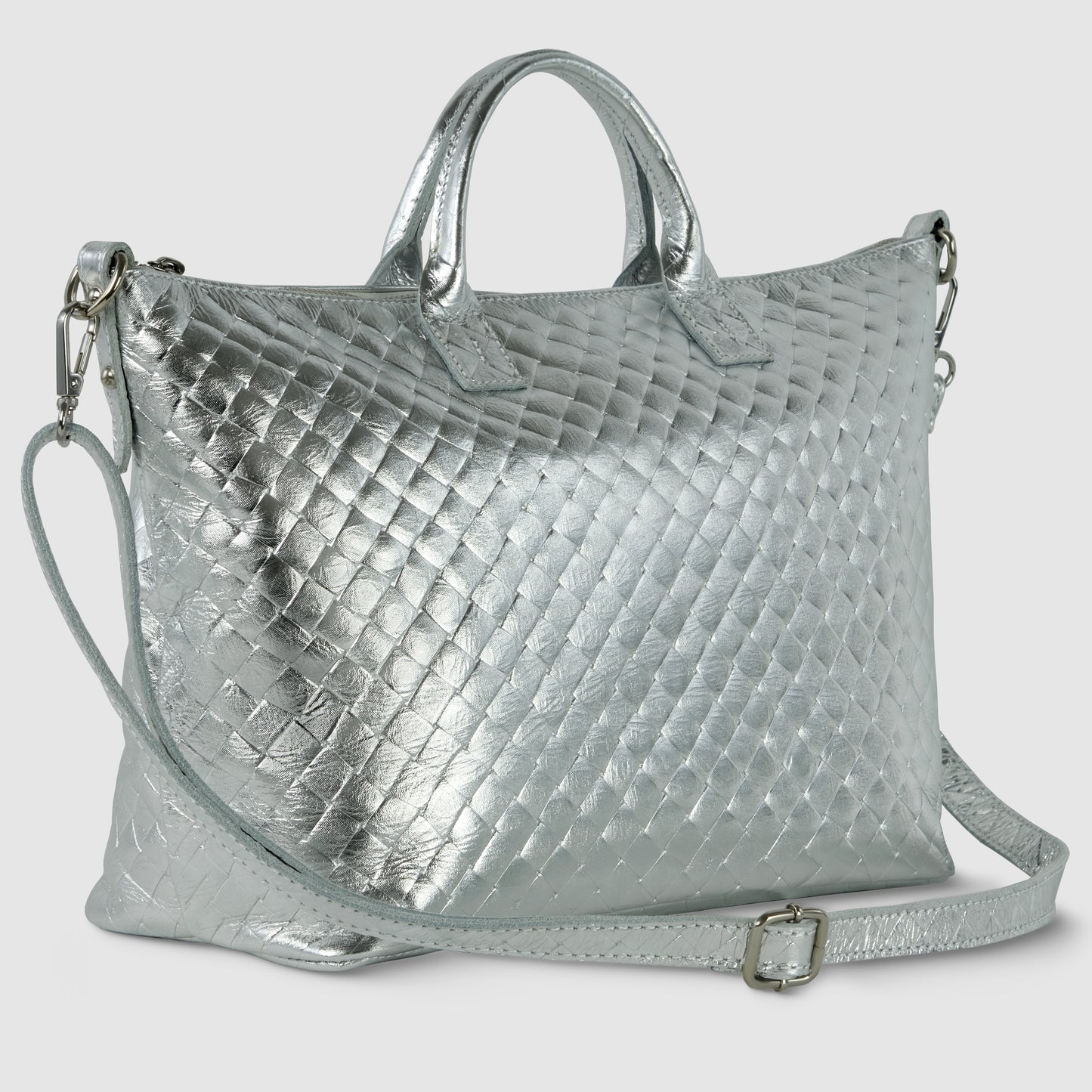A silver quilted handcrafted Italian handbag with two short handles and a detachable shoulder strap, featuring a shiny metallic finish and a diamond-patterned texture.