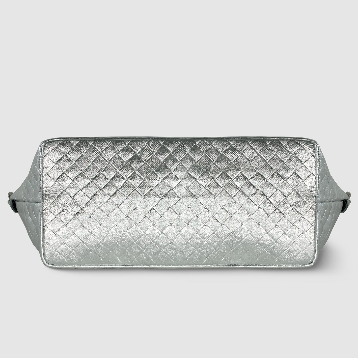 A rectangular silver quilted bag with a diamond-patterned texture, this handcrafted Italian handbag is shown from the bottom against a light gray background.